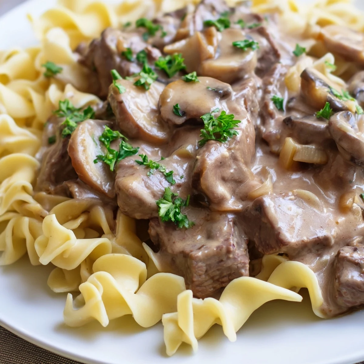 Tender beef strips and cremini mushrooms in a creamy gravy served over egg noodles for a comforting Beef Stroganoff dinner.