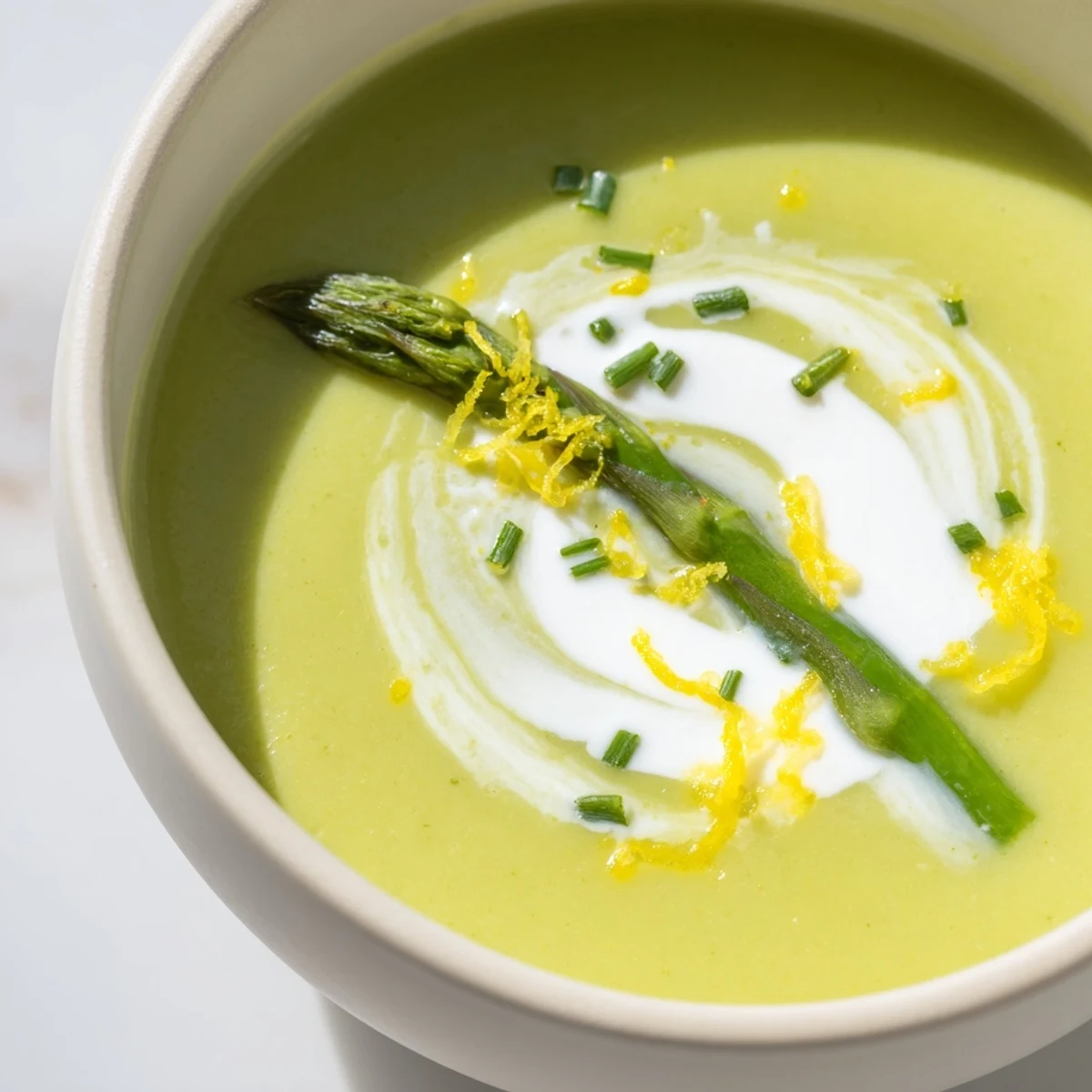 Creamy Asparagus Soup with Lemon and Crème Fraîche garnished with fresh dill in a rustic bowl.