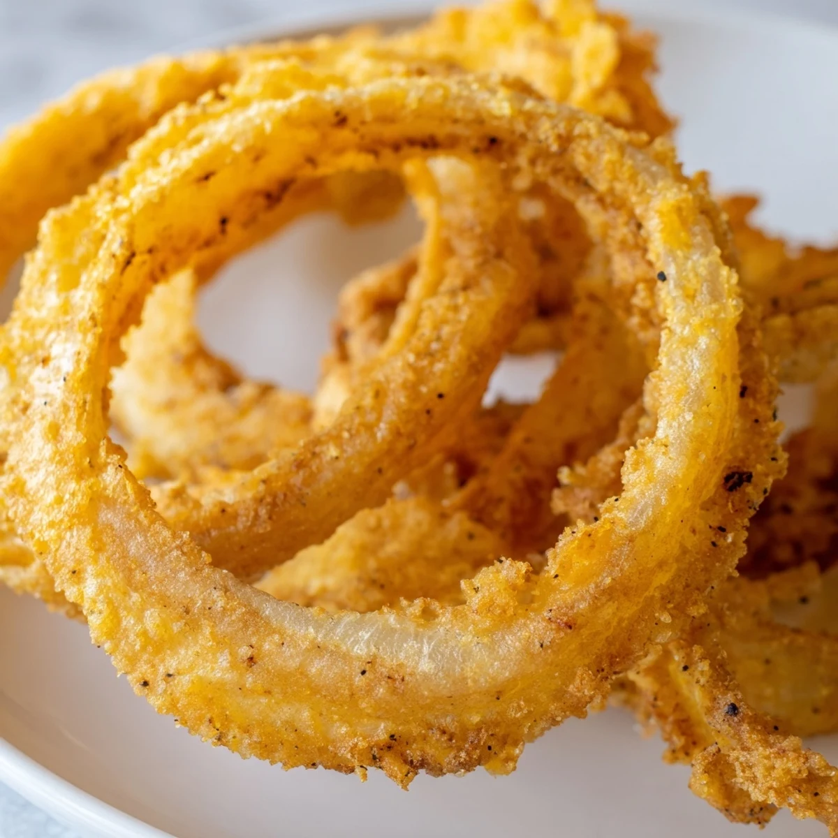 Crispy Onion Rings with Batter glistening with sea salt on a wooden board.