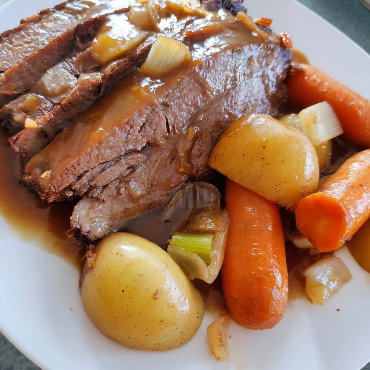 Juicy Slow Cooker Pot Roast with Carrots beside celery, onions, and herbs in a slow cooker.