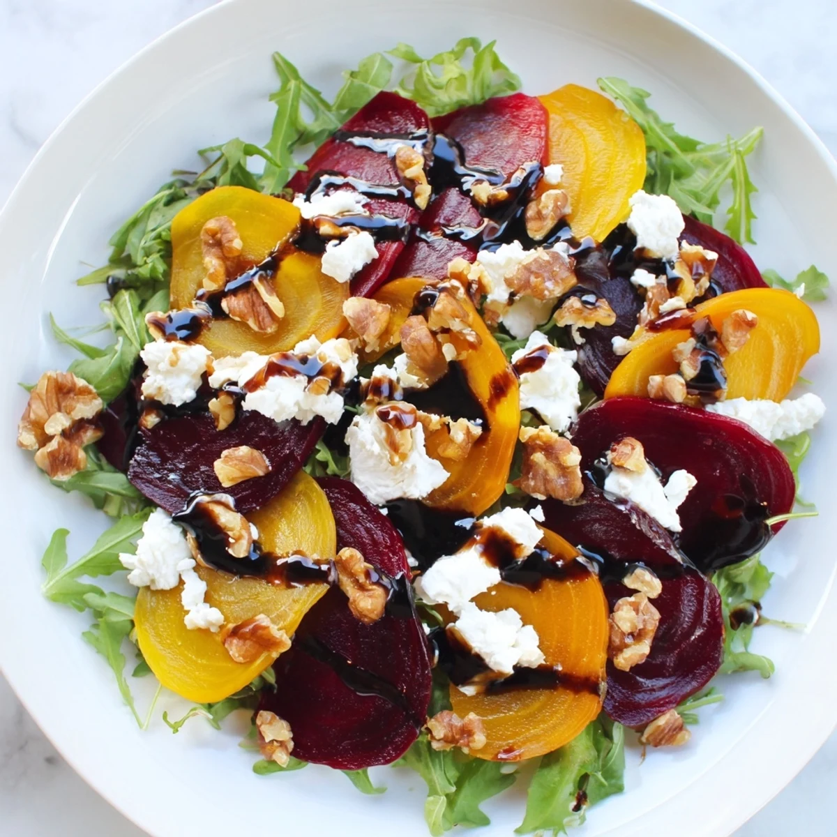 Roasted red and golden beets create a vibrant base for the Valentine Beet and Goat Cheese Salad on a dark platter. 