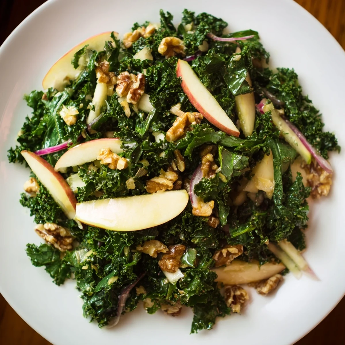 Vibrant green kale salad with crisp apple slices, toasted walnuts, and tangy feta, drizzled with maple-Dijon dressing for a refreshing side.  