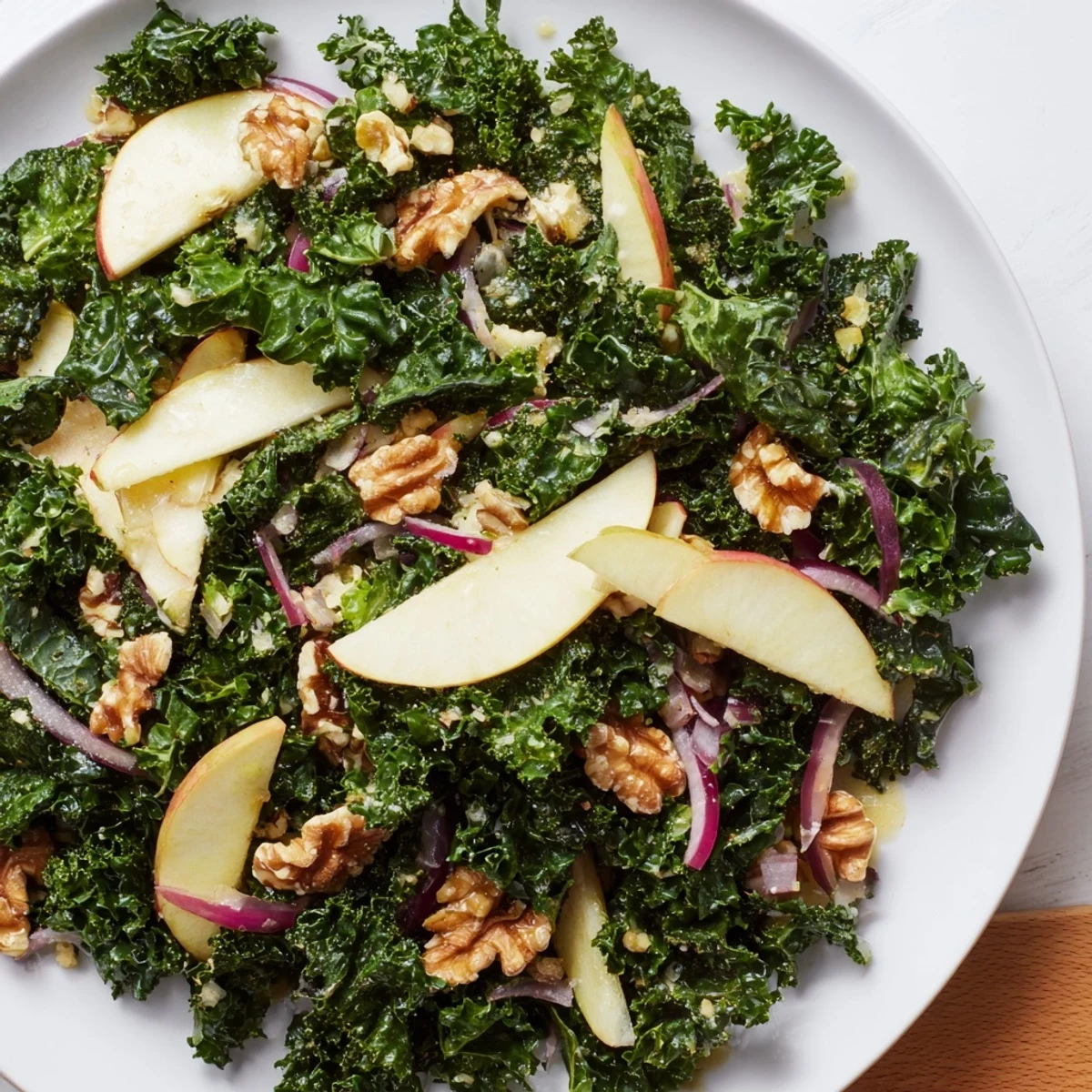 A close-up of the Green Kale and Apple Salad with Walnuts, showcasing colorful ingredients and a glossy, light-catching dressing.  