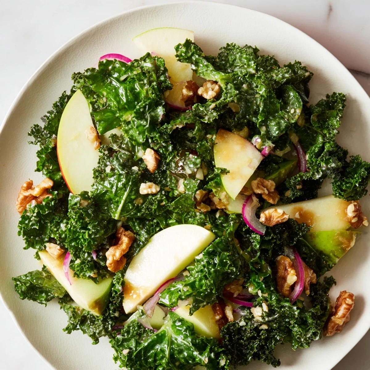 Hearty vegan kale and apple salad topped with crunchy walnuts and red onion, served in a rustic bowl for a healthy lunch.