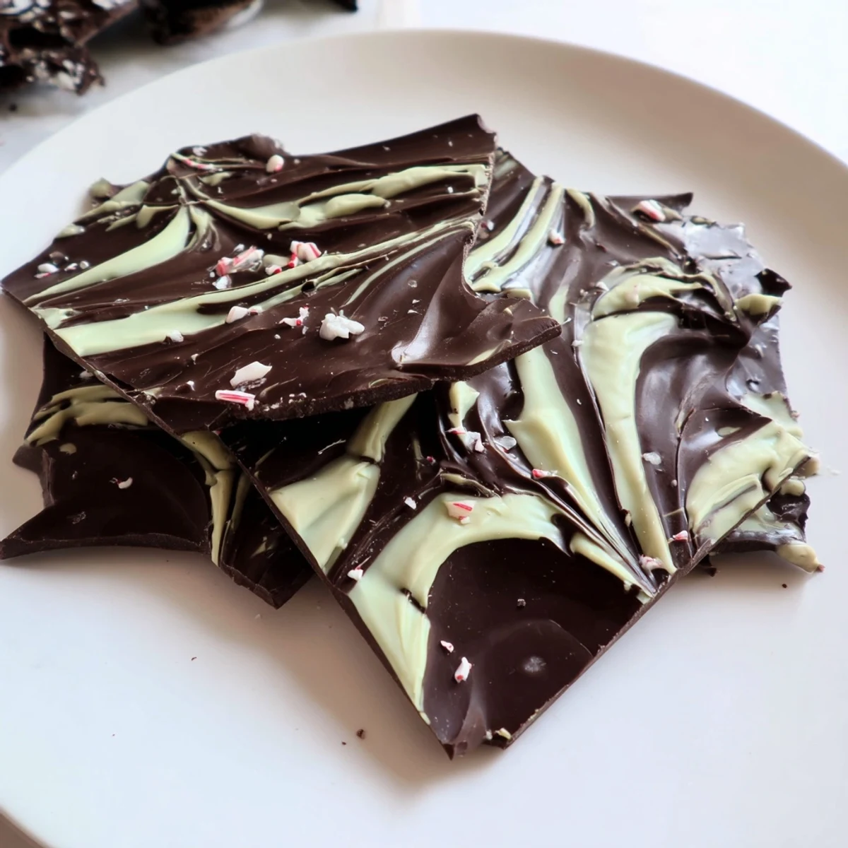 Mint chocolate bark with white chocolate swirls on a dark slate backdrop, ready to serve after chilling with a hot cup of coffee.  