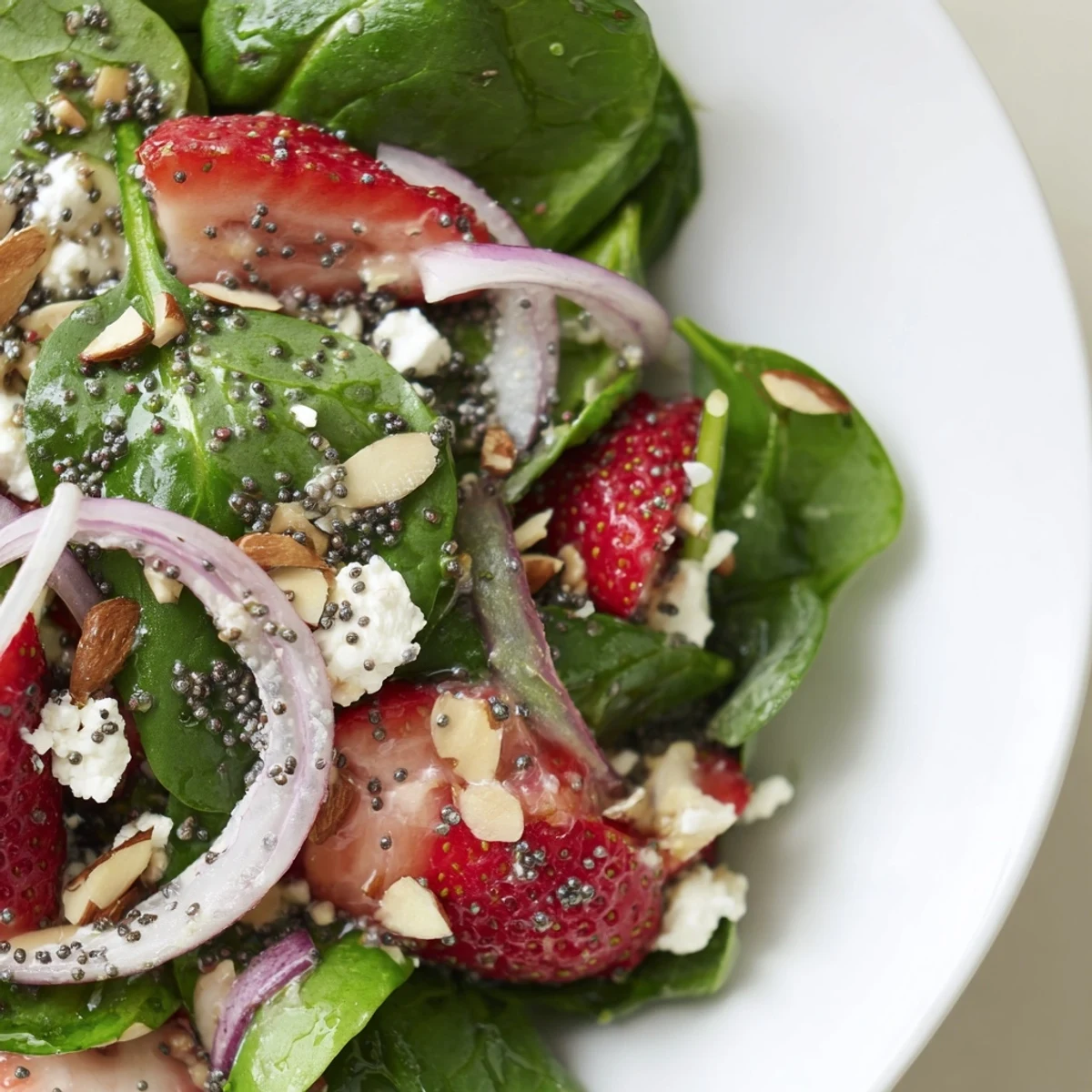 Fresh strawberries and baby spinach tossed in a tangy poppy seed dressing, topped with crumbled feta and toasted almonds for a vibrant salad.