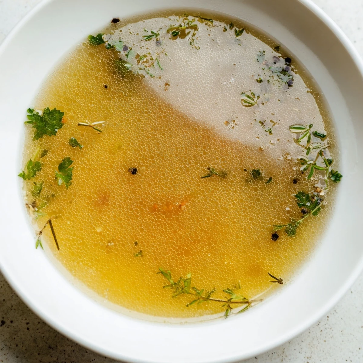 Steaming homemade vegetable broth with fresh herbs in a large pot, simmering with carrots and celery.  