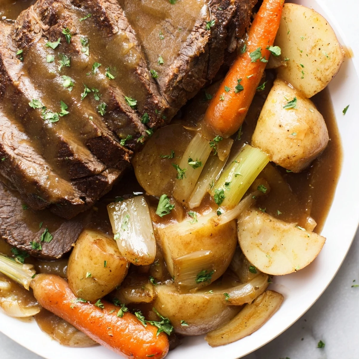 A hearty Slow Cooker Beef Pot Roast with Root Vegetables on a serving platter, surrounded by carrots, potatoes, and onions.
