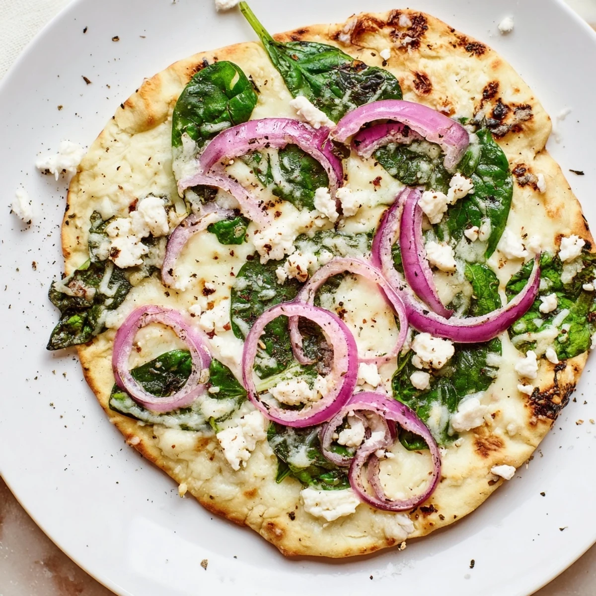 Golden, crispy flatbread pizza loaded with fresh spinach and creamy feta cheese, topped with melted mozzarella.