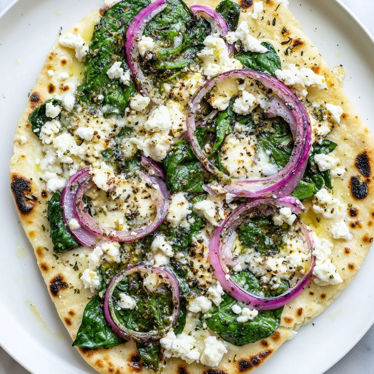 Savory flatbread pizza featuring fresh spinach and feta, baked until bubbly and golden on a baking sheet.