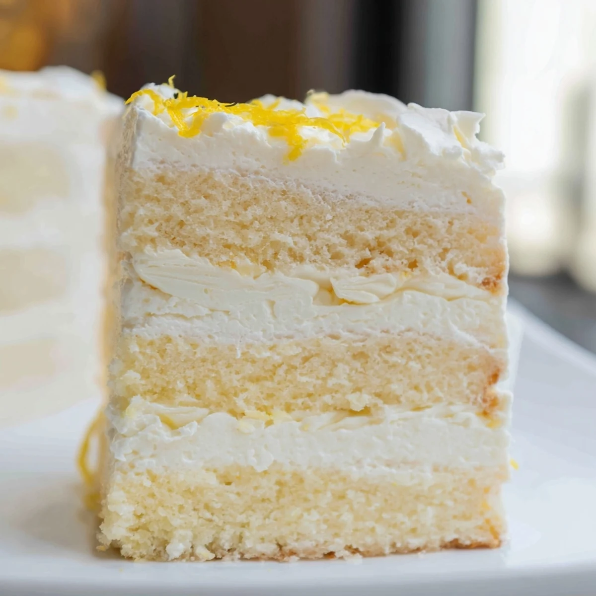 A slice of Limoncello Mascarpone Cake reveals moist sponge soaked in syrup and creamy mascarpone filling, next to a glass of Moscato.