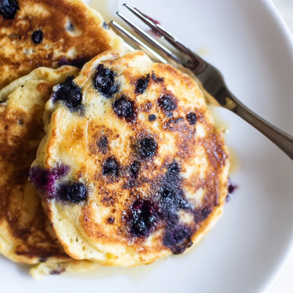 Fluffy Greek Yogurt Blueberry Pancakes served with extra berries and a dollop of yogurt for a protein-rich breakfast.
