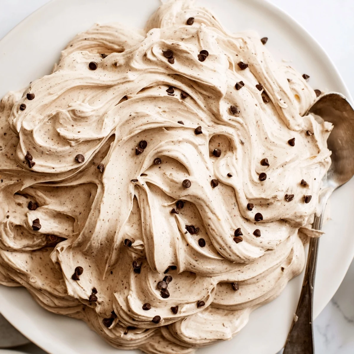 A close-up shot showcases smooth cookie dough frosting spreading over a rich chocolate cake layer with vibrant contrast.