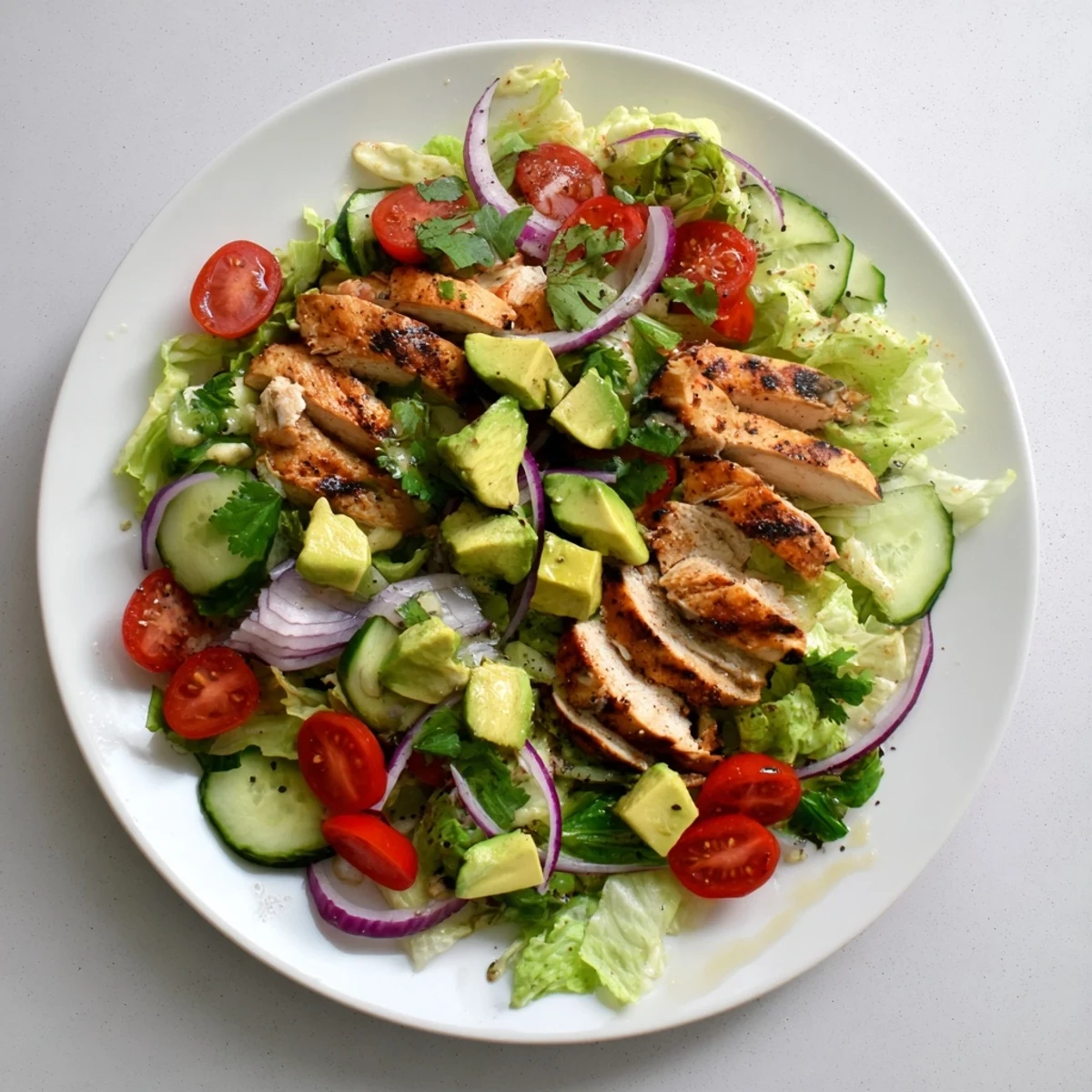 Close-up of Avocado Chicken Salad with tender chicken, cherry tomatoes, cucumber, and red onion tossed in a fresh, zesty dressing.