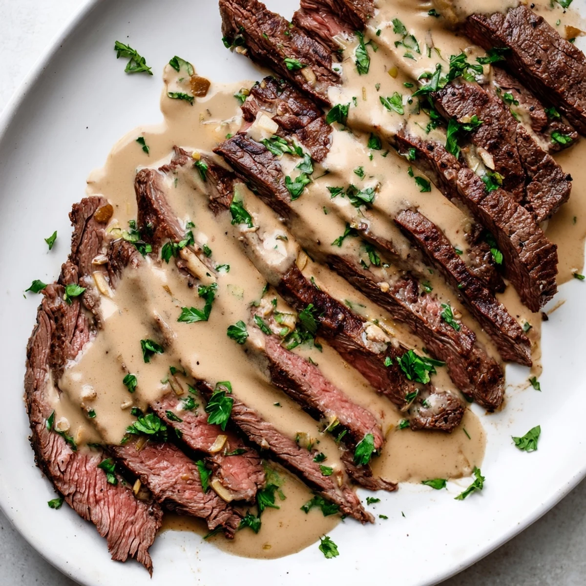 A close-up of juicy flank steak with roasted garlic sauce, served over creamy mashed potatoes on a rustic table.