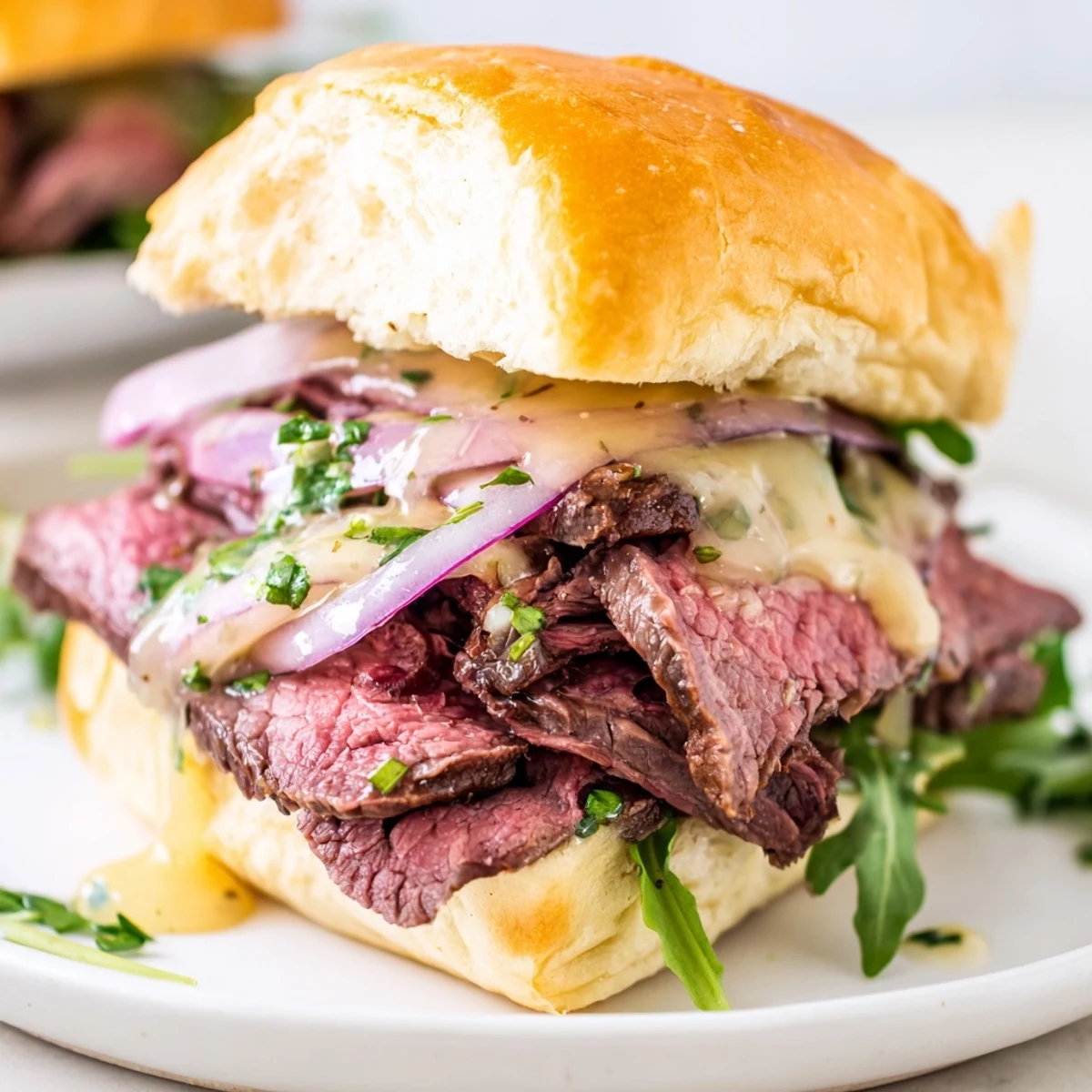 Tender seared steak sits on buns spread with homemade cowboy butter and onions.