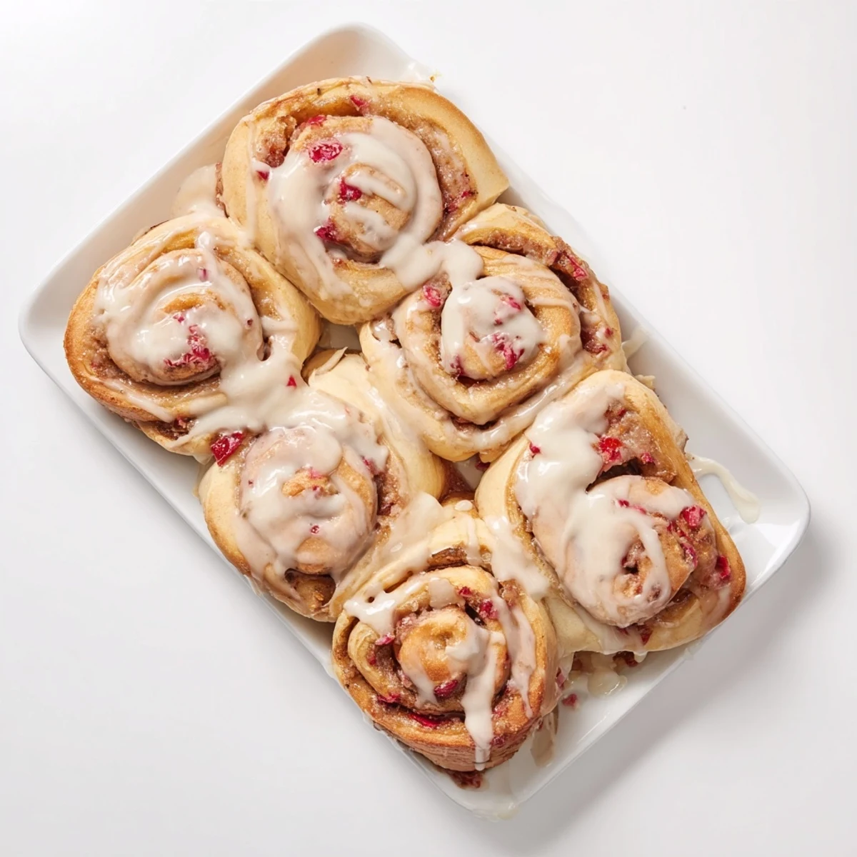 Golden breakfast pastry featuring spiraled strawberry cinnamon rolls sliced to reveal red fruit filling and glazed topping