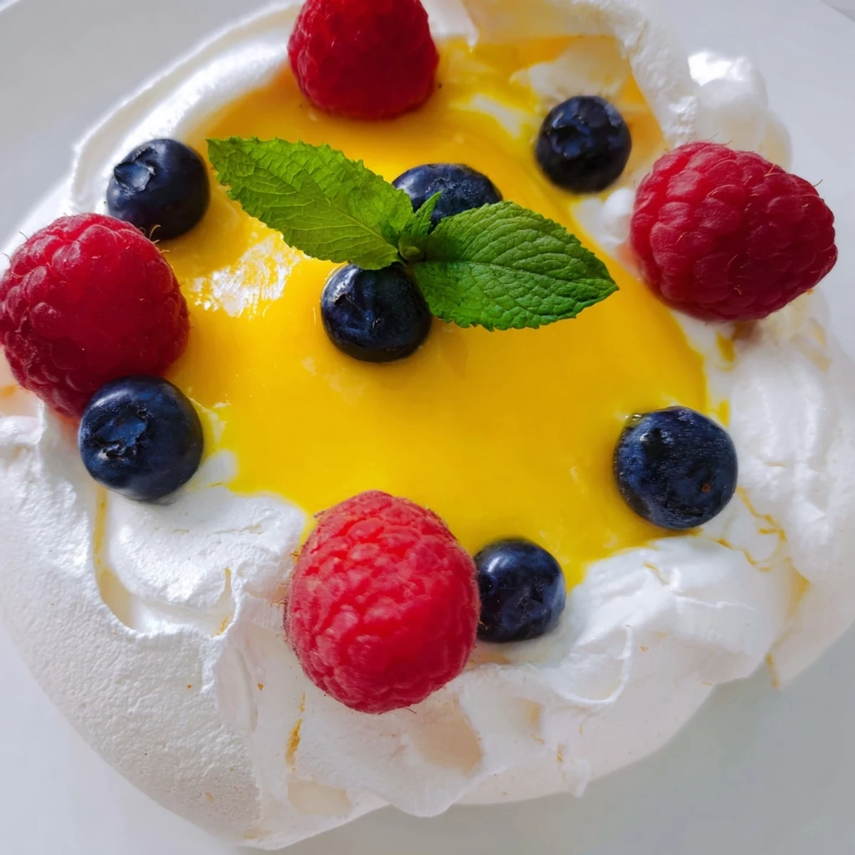 Airy baked meringues with citrus curd garnished with colorful fresh berries
