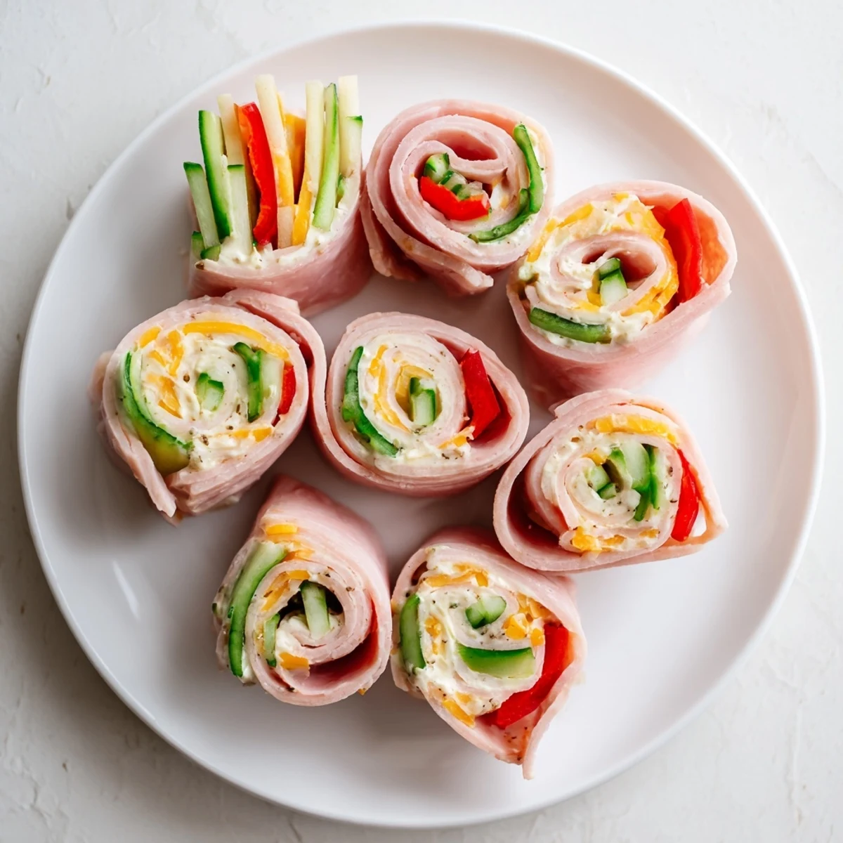 Colorful spiral keto ham roll ups with red pepper strips and cucumber