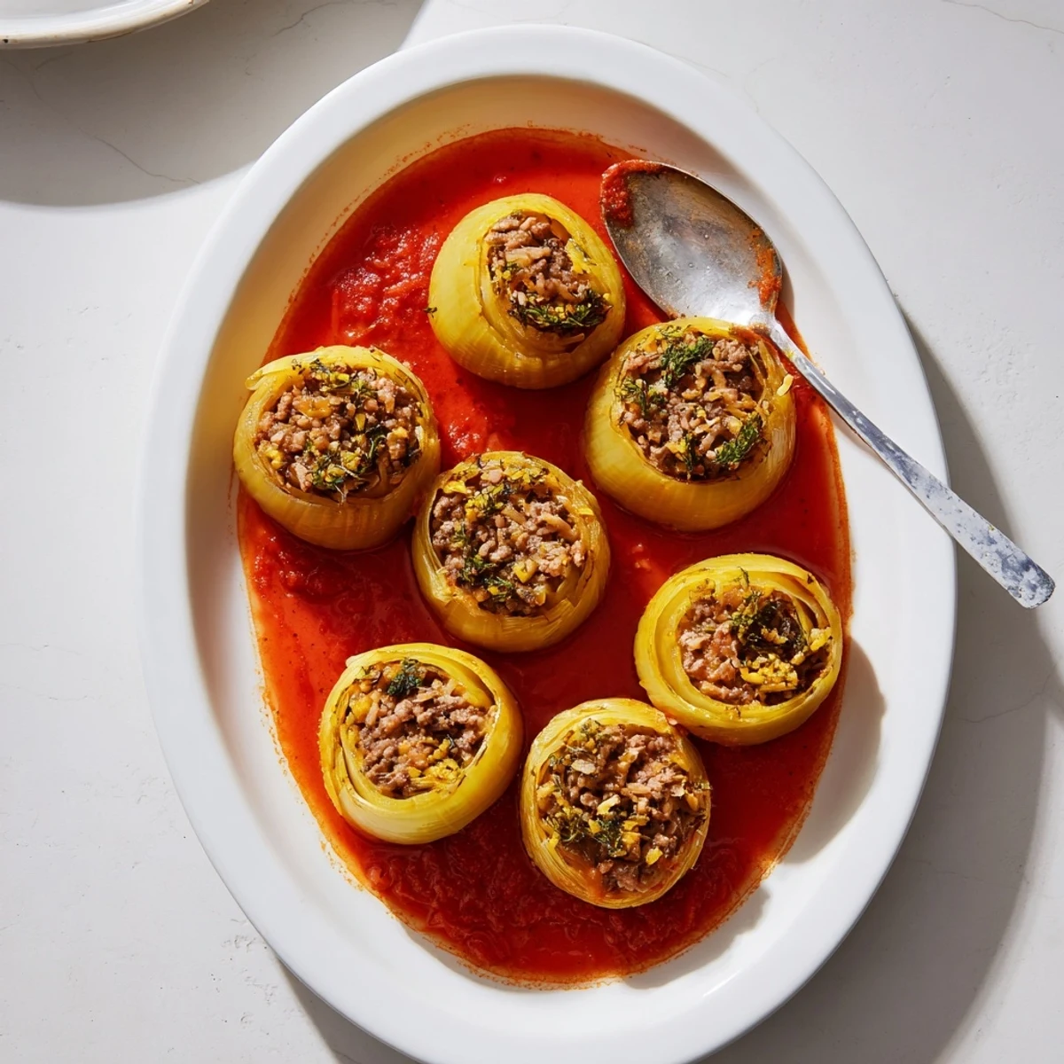Tender onion layers wrapped around savory ground beef and rice mixture in a baking dish
