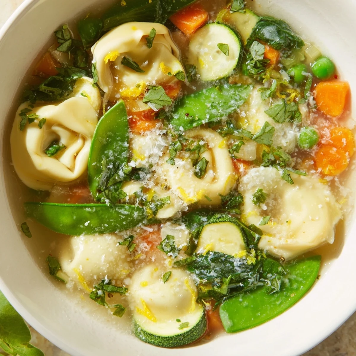 Vibrant vegetable tortellini soup featuring cheese-filled pasta, crisp snap peas, and wilted spinach