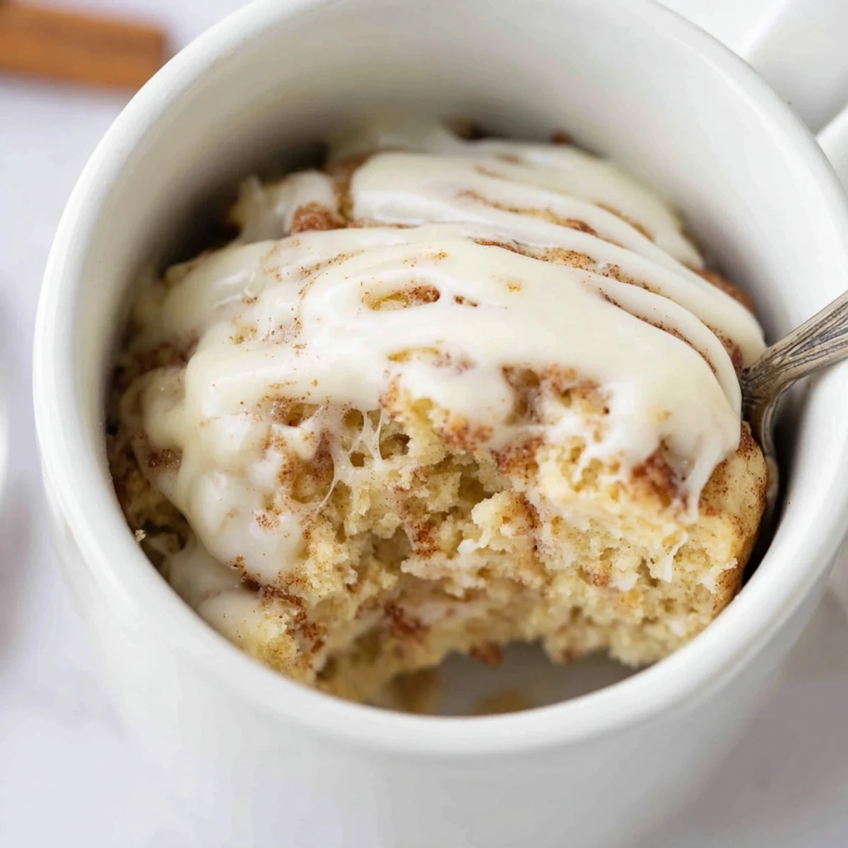 Warm cinnamon-swirled mug cake made with cottage cheese topped with sweet icing