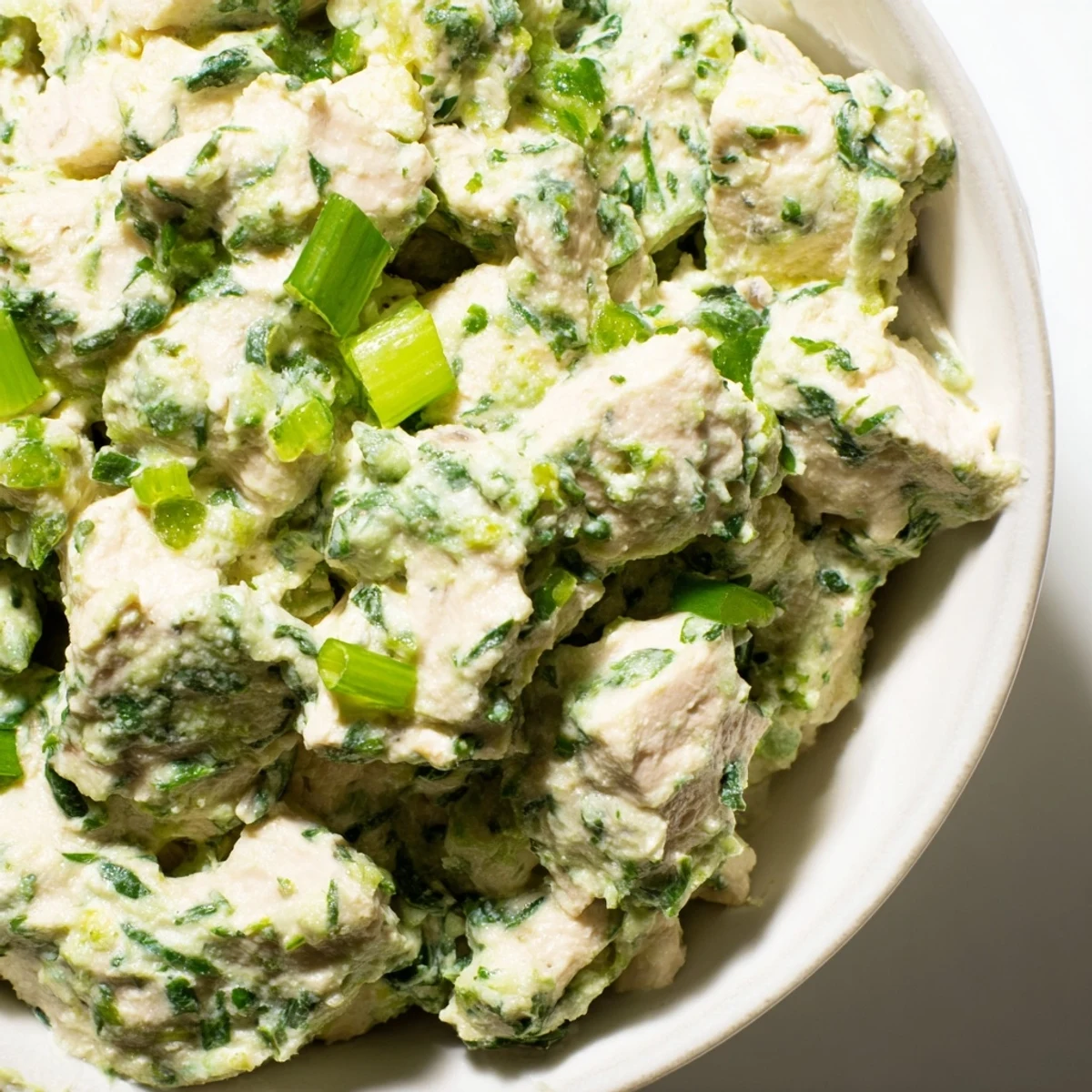 Creamy green goddess chicken salad dip topped with fresh herbs and sliced radishes on a serving platter