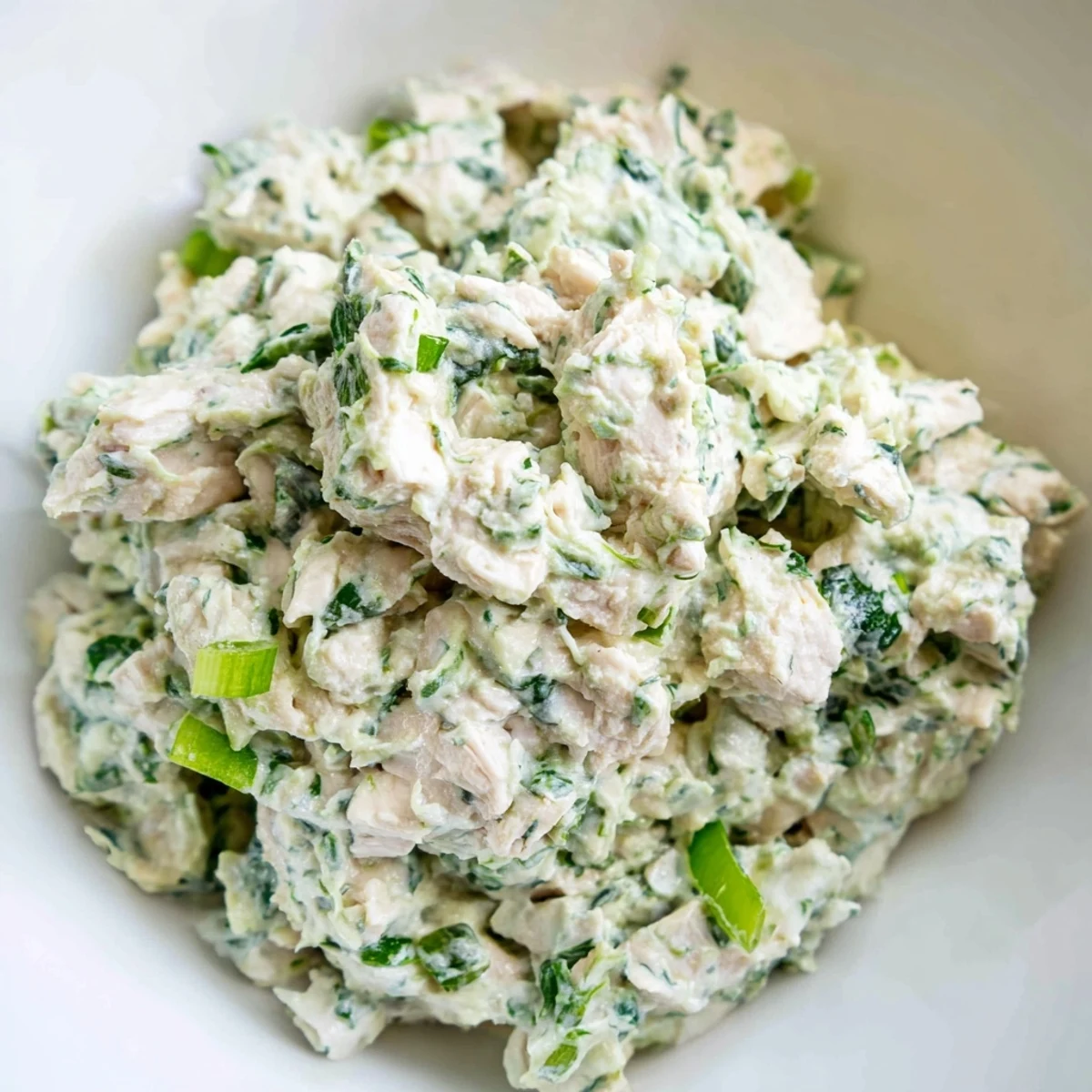 Golden chicken pieces folded into tangy green goddess dressing garnished with cucumber slices and fresh chives