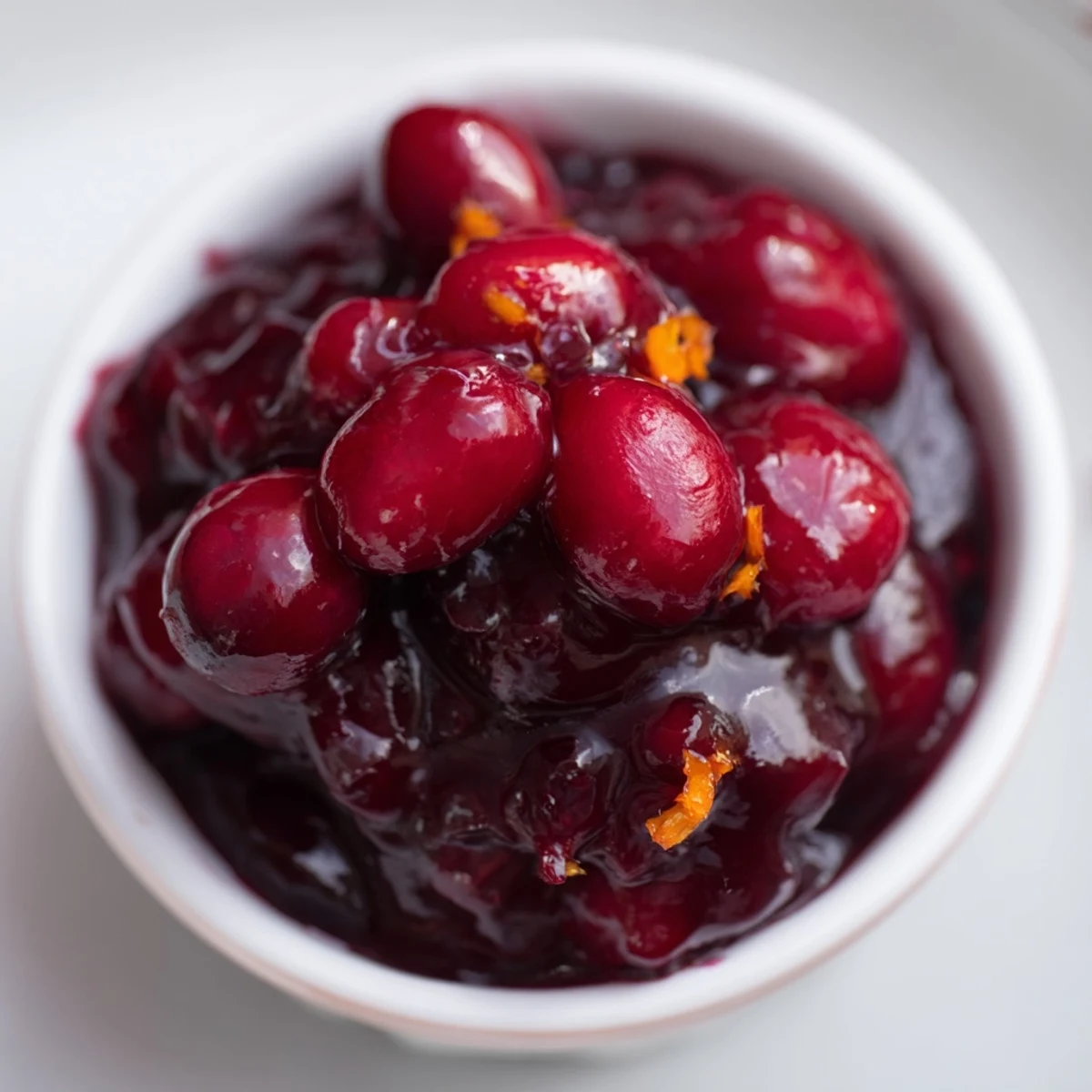 Deep crimson homemade cranberry sauce ladled into a decorative glass dish for holiday entertaining