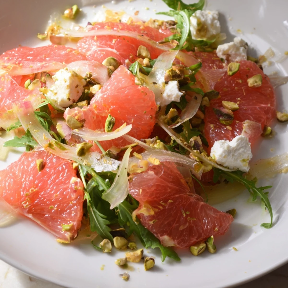 Colorful grapefruit goat cheese and fennel salad in a bowl showcasing segmented fruit and shaved fennel over arugula