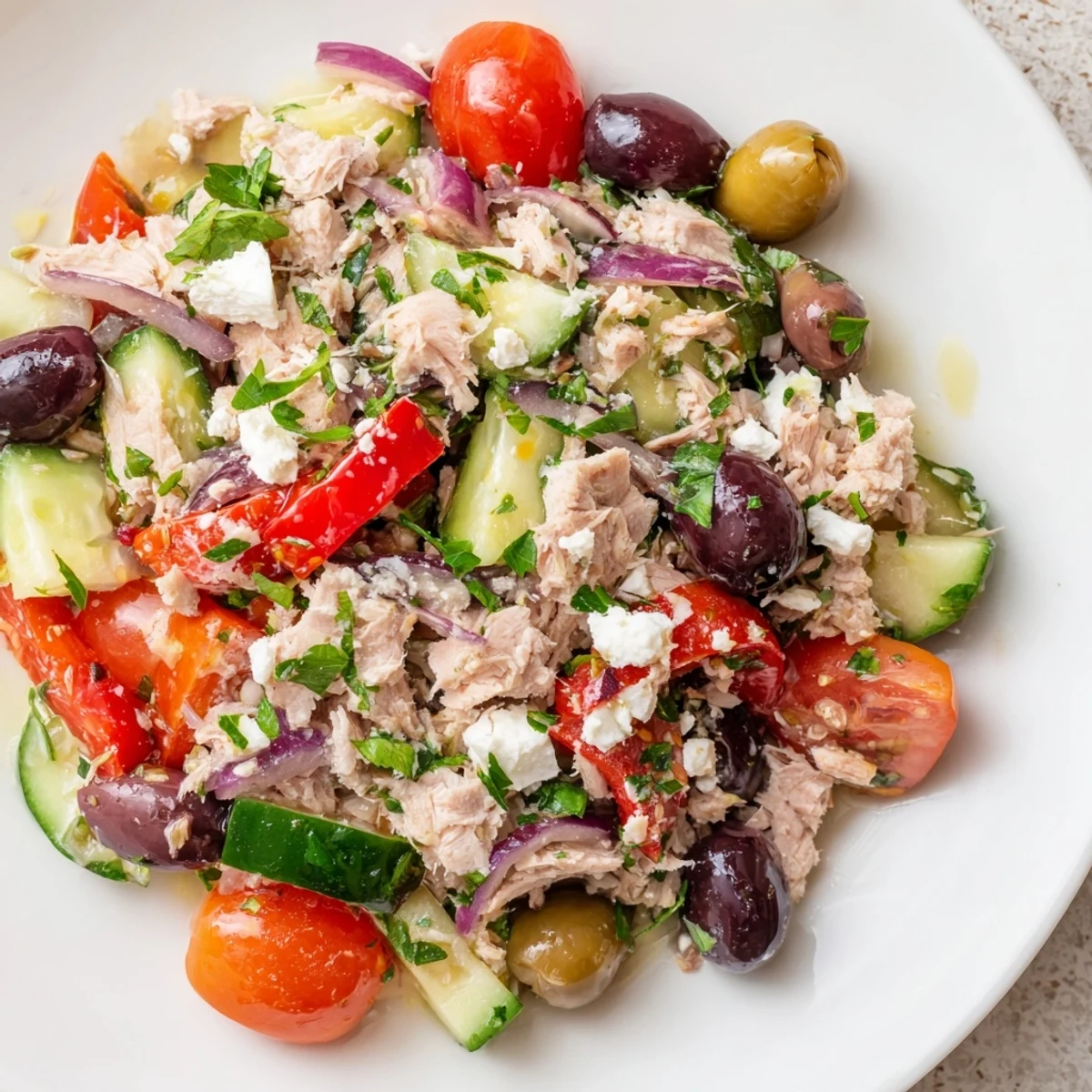 Vibrant bowl of Mediterranean tuna salad topped with olives, roasted peppers, and herbs