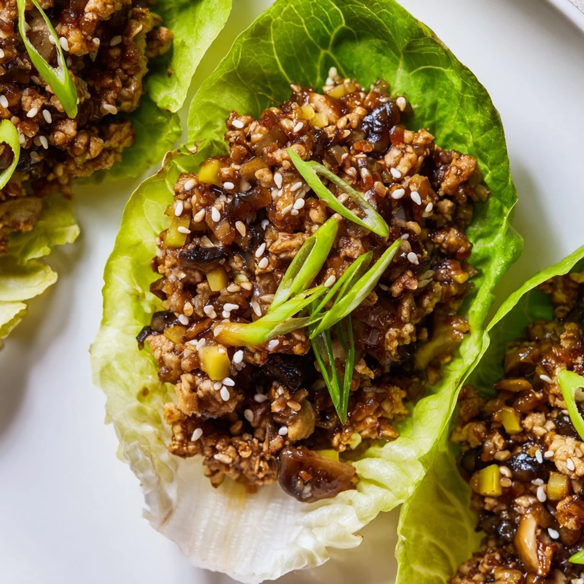 Glossy hoisin glazed chicken filling spooned into crunchy lettuce wraps garnished with sesame seeds