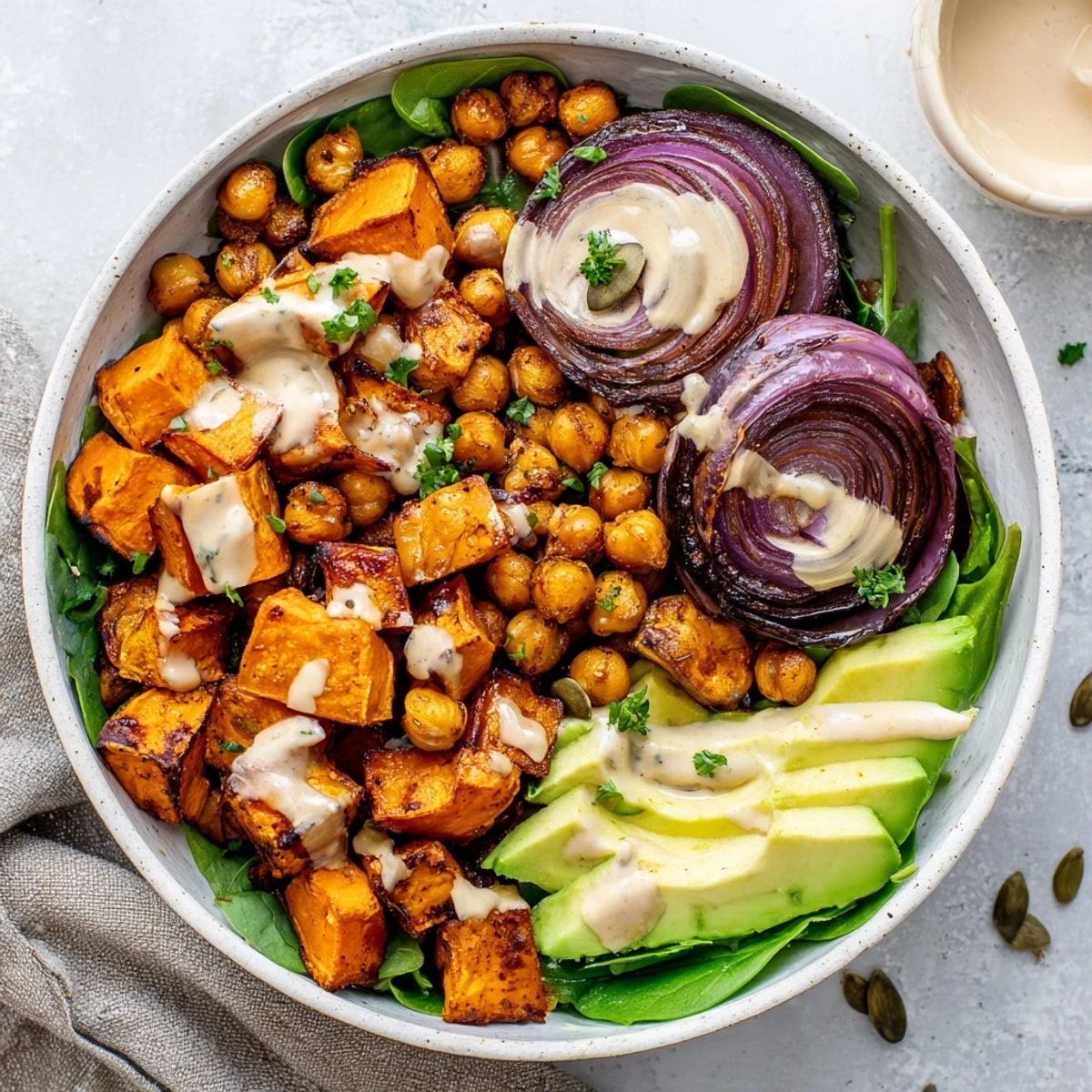 Golden roasted sweet potatoes and crispy chickpeas drizzled with creamy tahini dressing over fresh greens