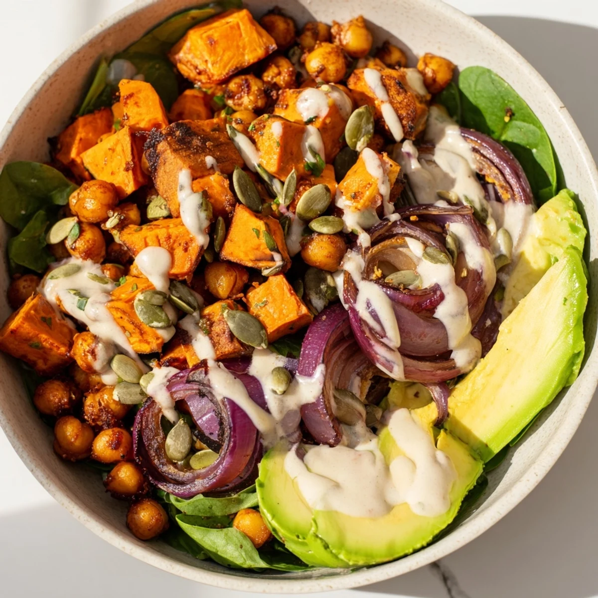 Wholesome vegetarian bowl featuring caramelized sweet potatoes and spiced chickpeas served with tahini dressing