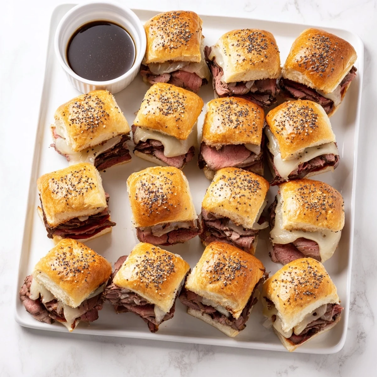 Golden brown French dip sliders loaded with roast beef, caramelized onions, and melted provolone cheese