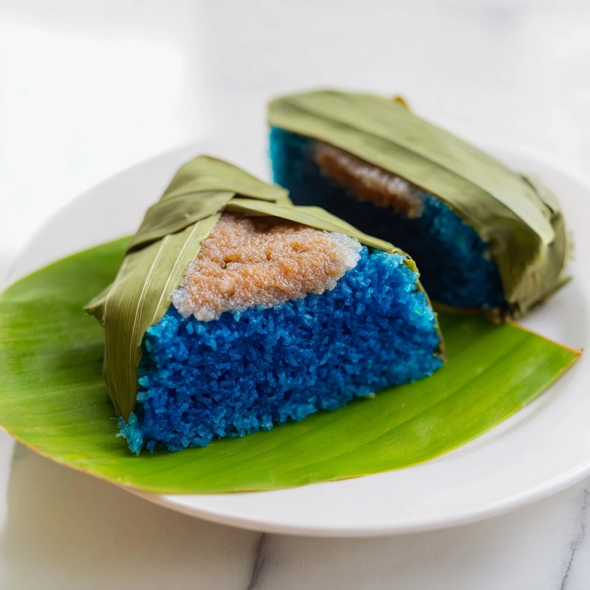 Traditional Malaysian Pulut Inti kuih showing fragrant palm sugar coconut mixture atop sticky blue rice squares