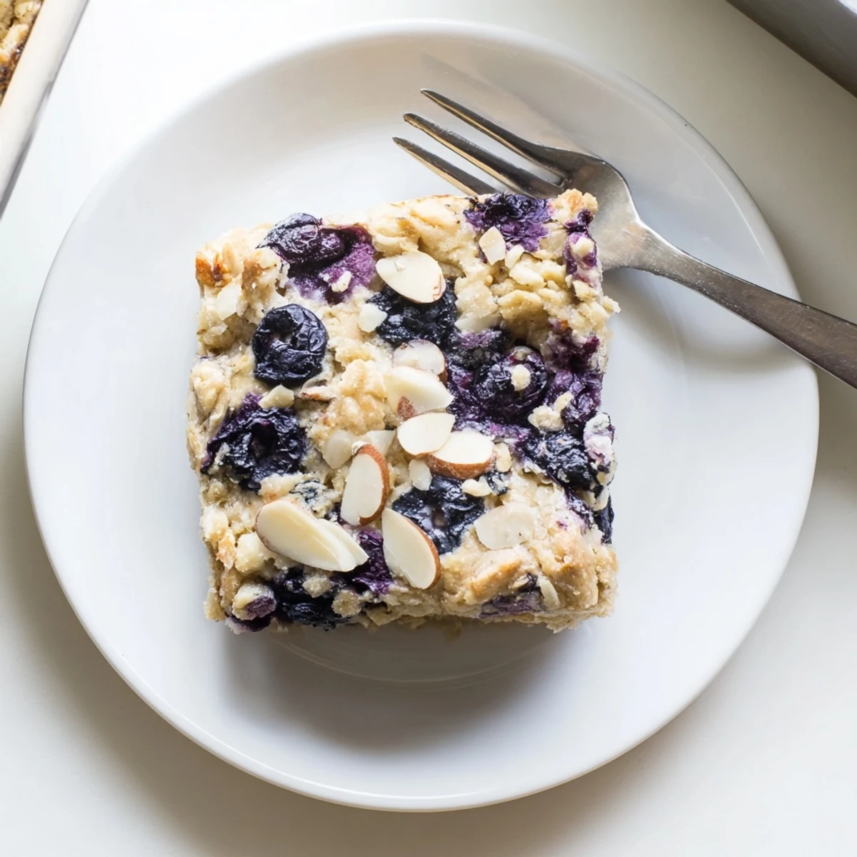 Sliced square of warm blueberry cottage cheese breakfast bake with fresh blueberries scattered