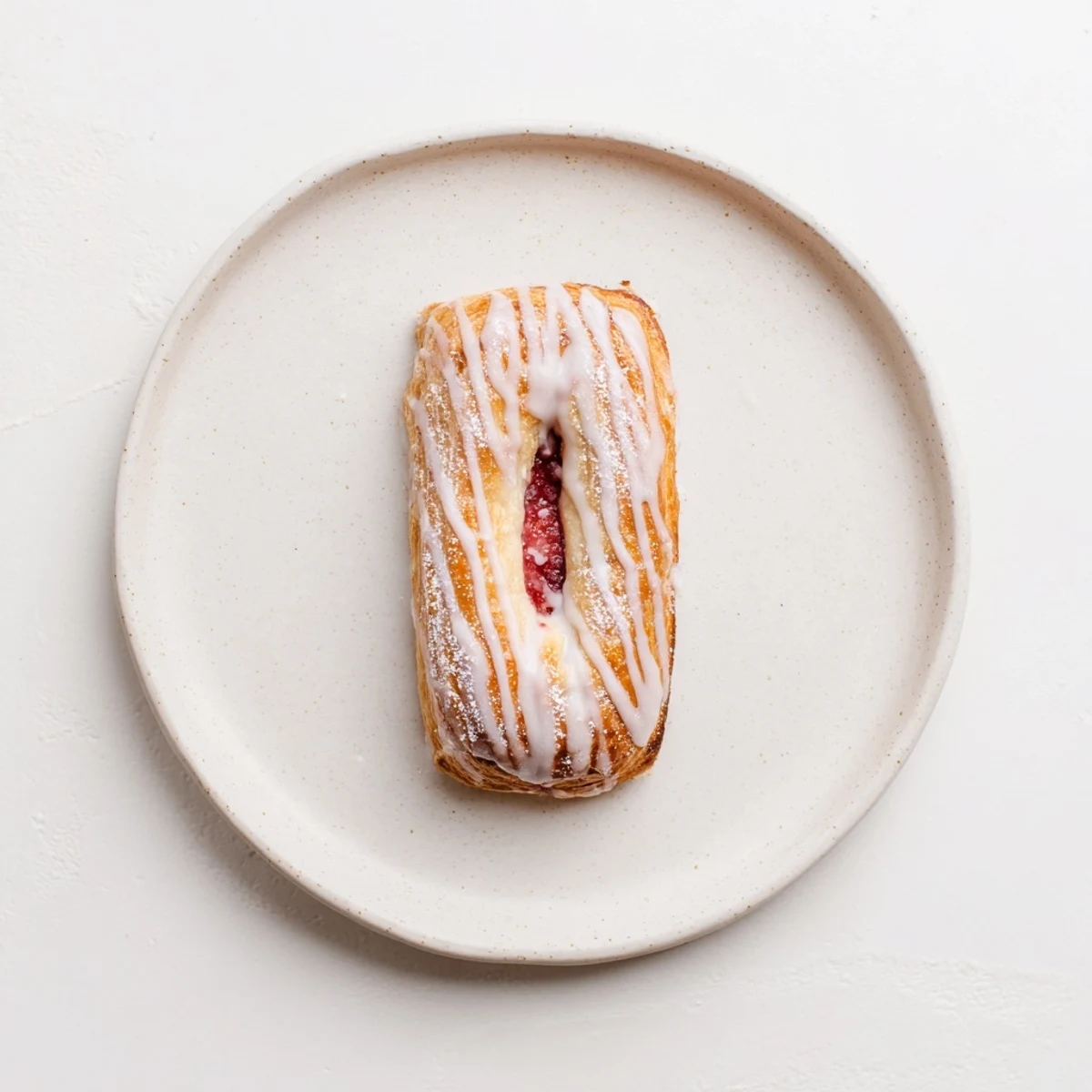 Golden sourdough discard raspberry cream cheese danishes drizzled with sweet vanilla glaze on a rustic baking sheet