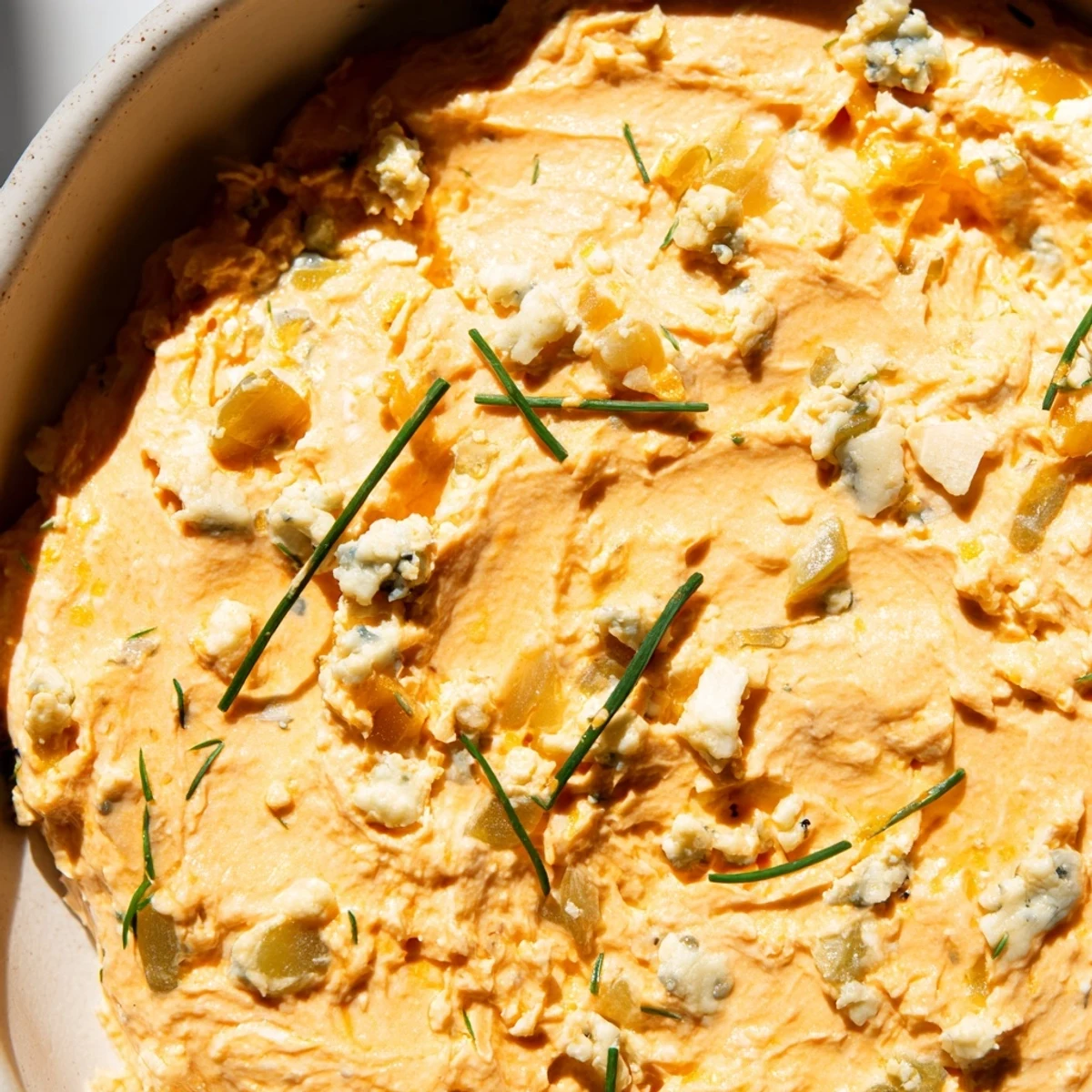 Creamy buffalo pickle dip served in a bowl with crisp celery sticks and crunchy chips nearby