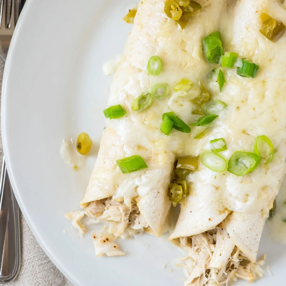 Baked Creamy White Chicken Enchiladas with velvety sauce, ideal for family dinners.
