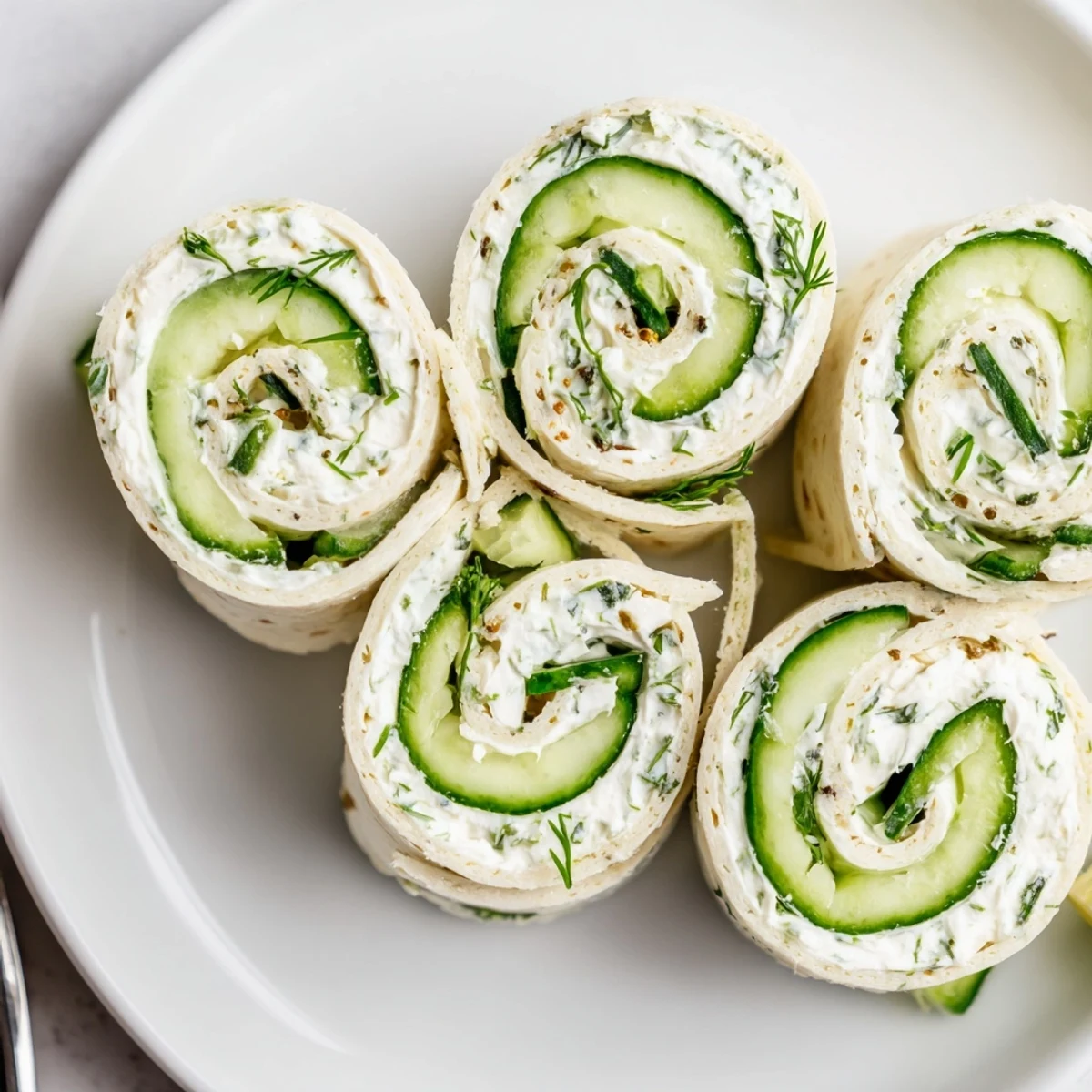Cucumber And Dill Pinwheels on a platter, crisp cucumbers and creamy dill.
