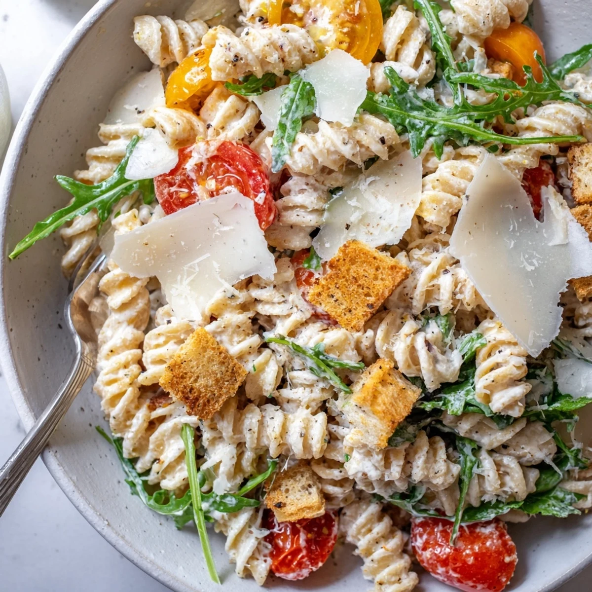 Arugula Pasta Caesar Salad tossed in creamy dressing with shaved Parmesan  