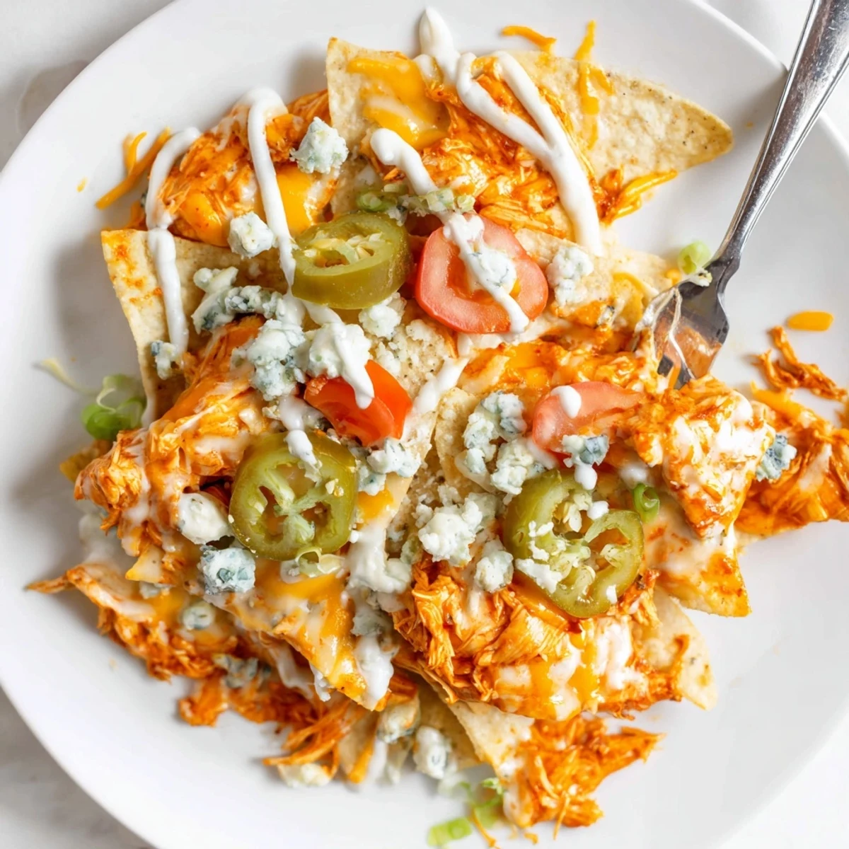 Zesty Buffalo Chicken Nachos on crispy tortilla chips, topped with tomatoes, green onions