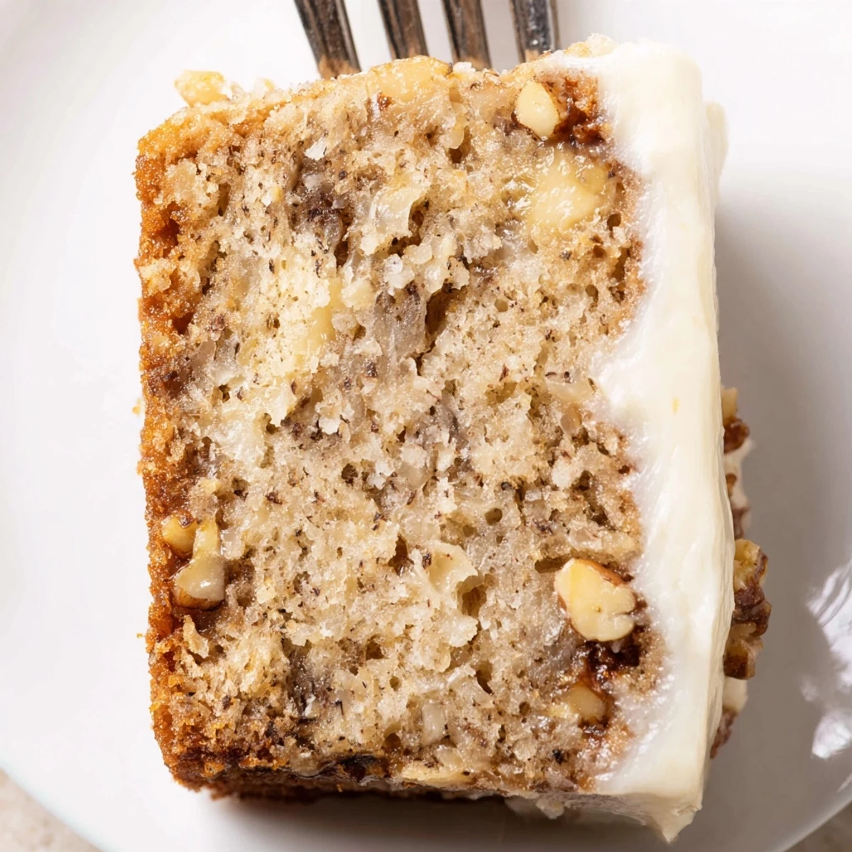 Sliced Moist Banana Cake steaming faintly, tangy cream cheese frosting optional.