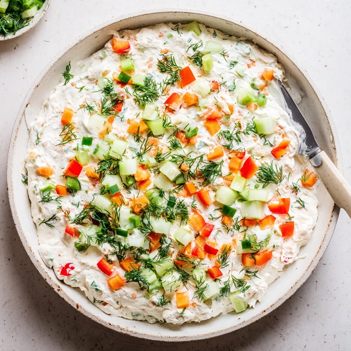 Creamy garden vegetable spread topped with colorful diced vegetables served on a wooden board