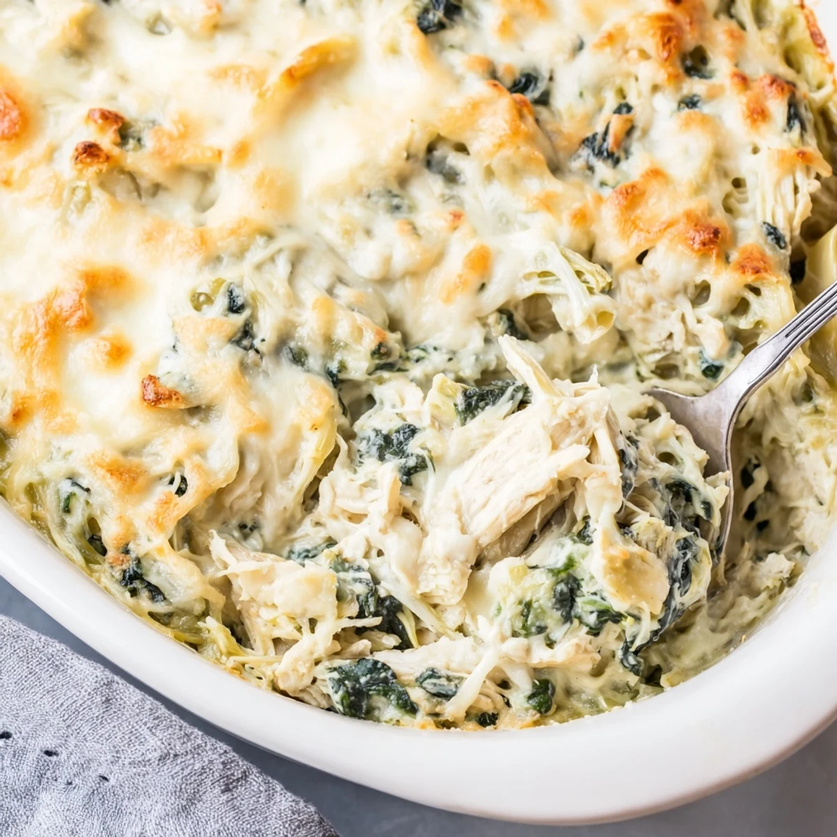 Golden brown Spinach Artichoke Chicken Casserole bubbling with melted mozzarella cheese in a baking dish