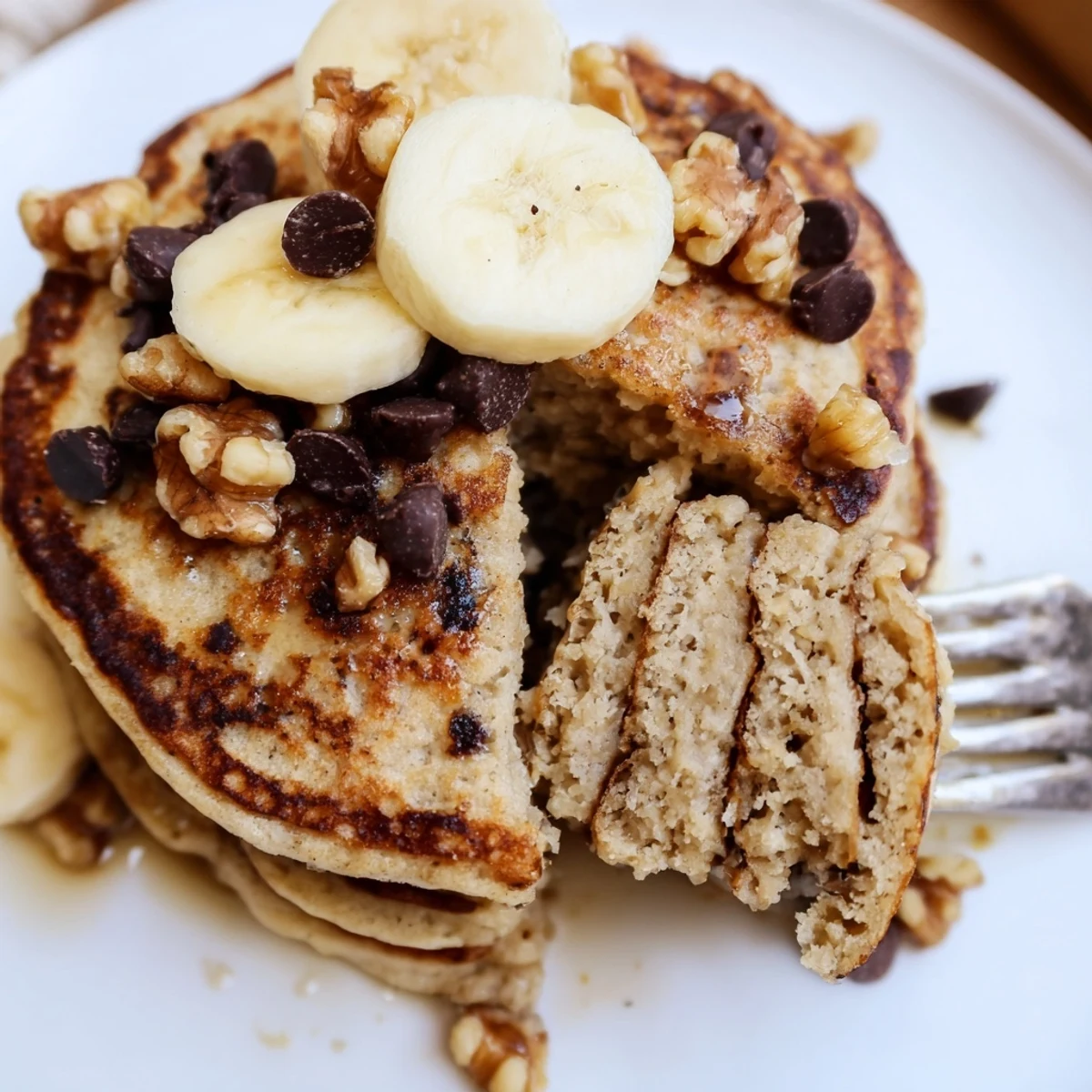 Healthy protein banana pancakes cooking on a griddle with bubbles forming on the surface, ready to flip