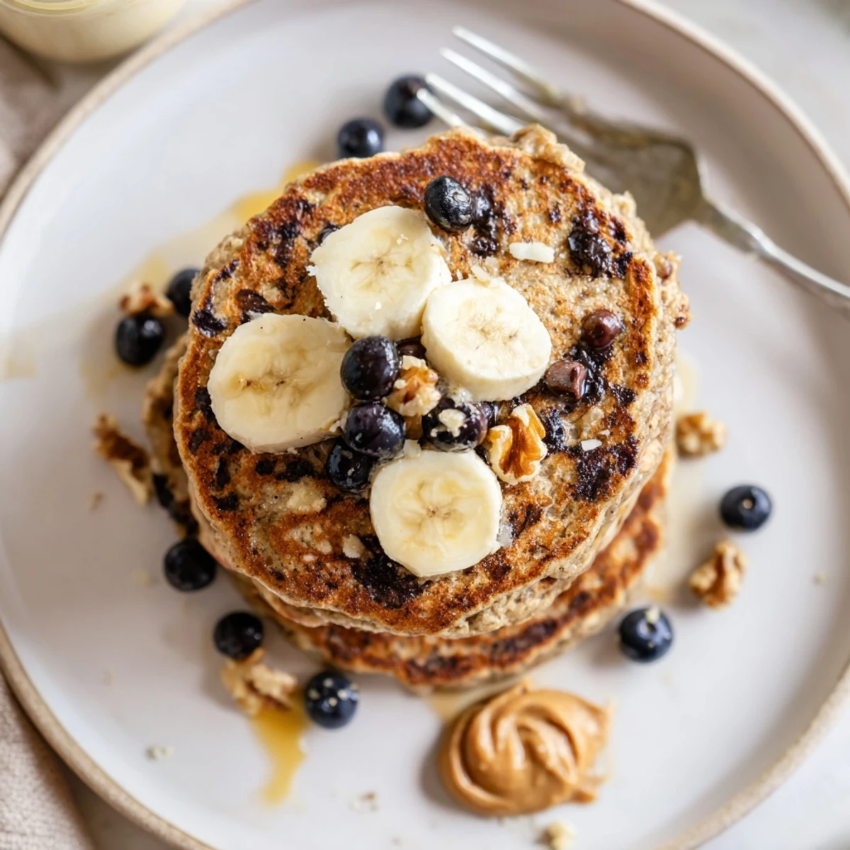 Plate of Protein Banana Pancakes garnished with berries and creamy nut butter
