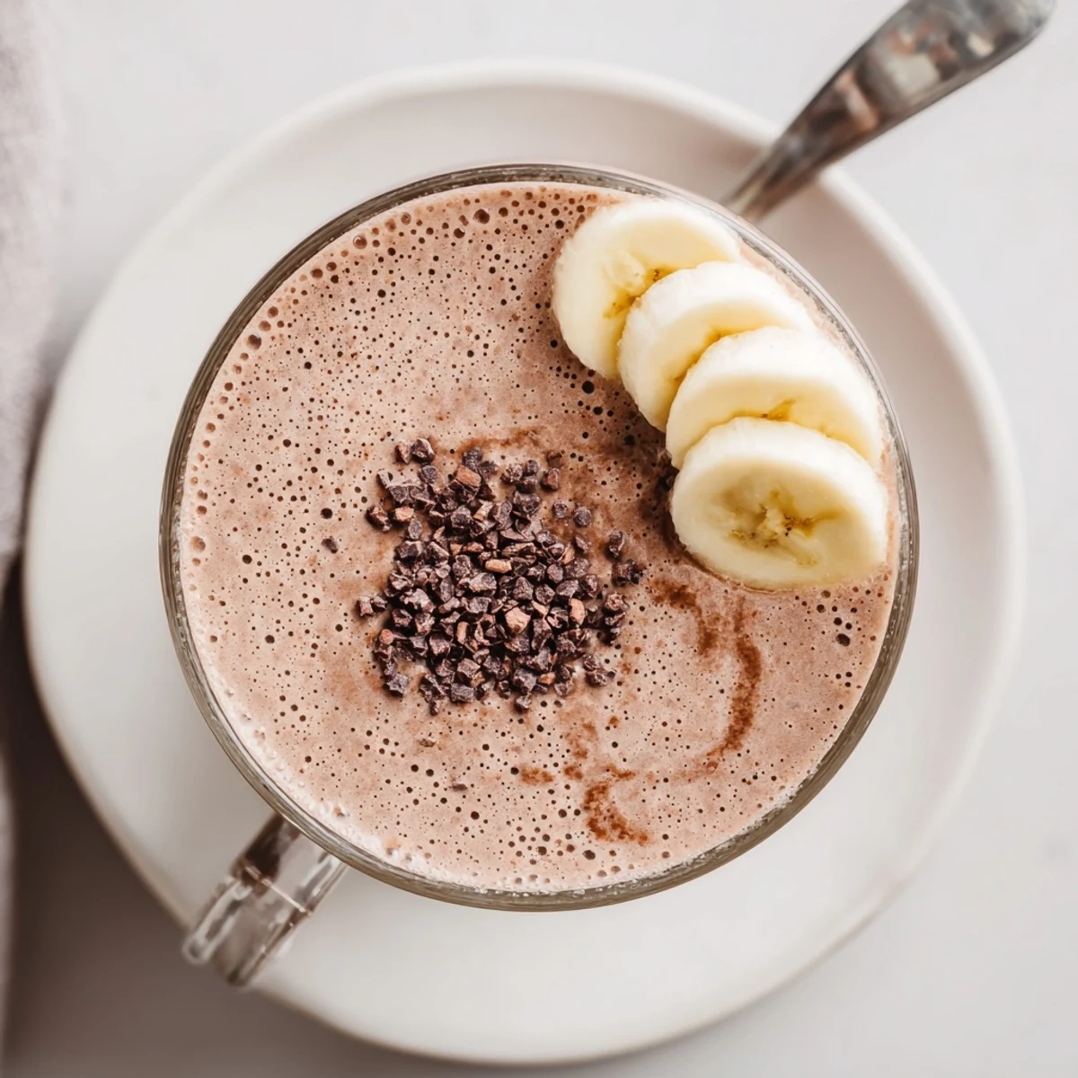 Raw Chocolate Banana Shake in tall glass, creamy texture, banana slices garnish