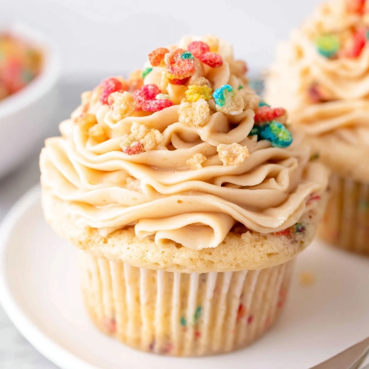 Swirled Fruity Pebbles Cereal Frosting piped onto cooled cupcakes, sweet aroma